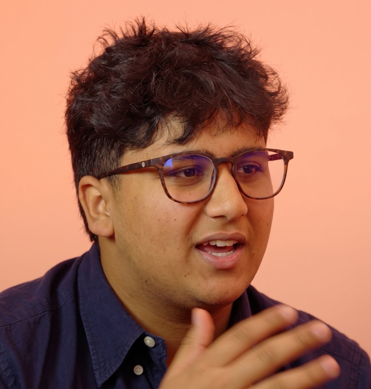 Aryan mid-conversation, in glasses and a navy shirt